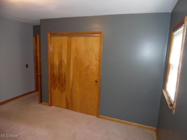 unfurnished bedroom with a closet, carpet flooring, and baseboards