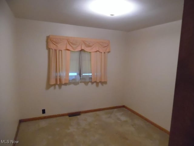 carpeted empty room featuring visible vents and baseboards