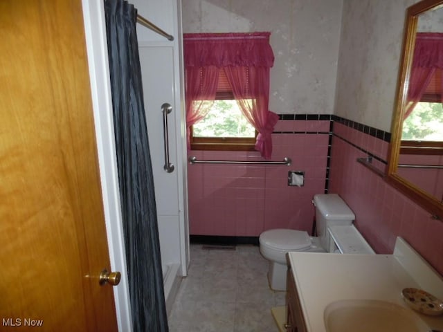 bathroom with a wainscoted wall, toilet, plenty of natural light, and vanity