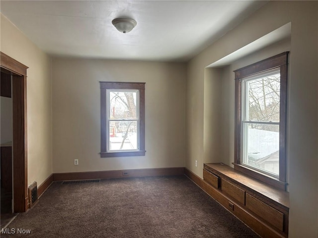 unfurnished room featuring dark colored carpet and baseboards