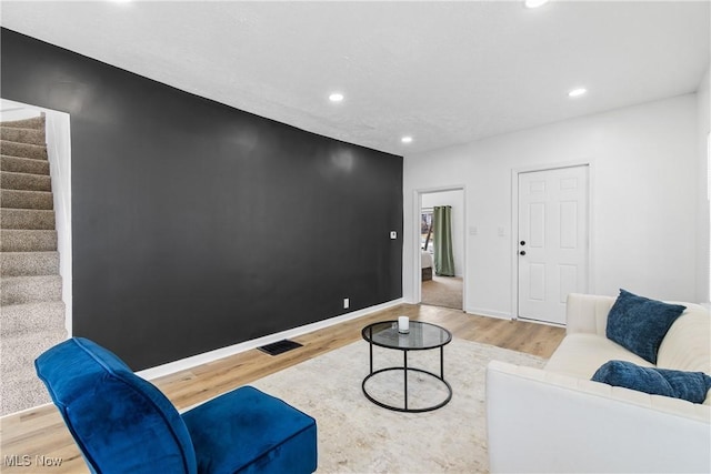 living room featuring recessed lighting, visible vents, wood finished floors, baseboards, and stairs