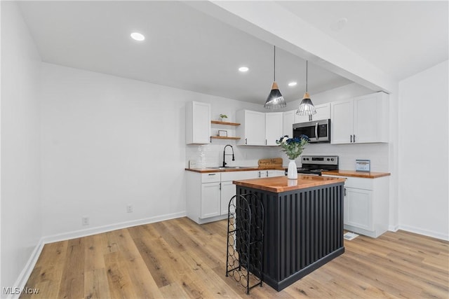 kitchen with a breakfast bar, wood counters, white cabinetry, appliances with stainless steel finishes, and open shelves