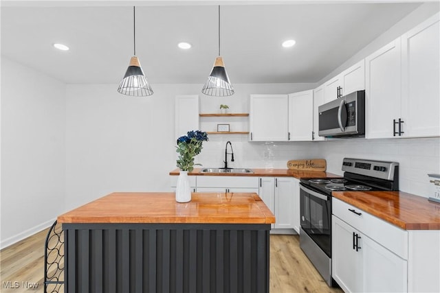 kitchen featuring wood counters, a kitchen island, stainless steel appliances, open shelves, and a sink