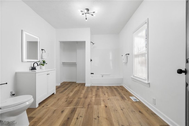 bathroom featuring toilet, wood finished floors, vanity, baseboards, and tub / shower combination