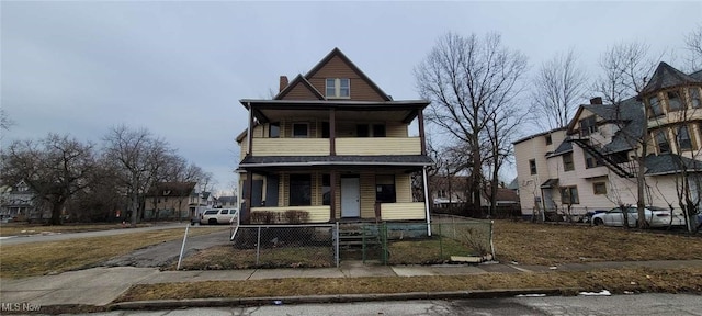 view of front of home featuring a porch, a fenced front yard, a balcony, a gate, and a chimney