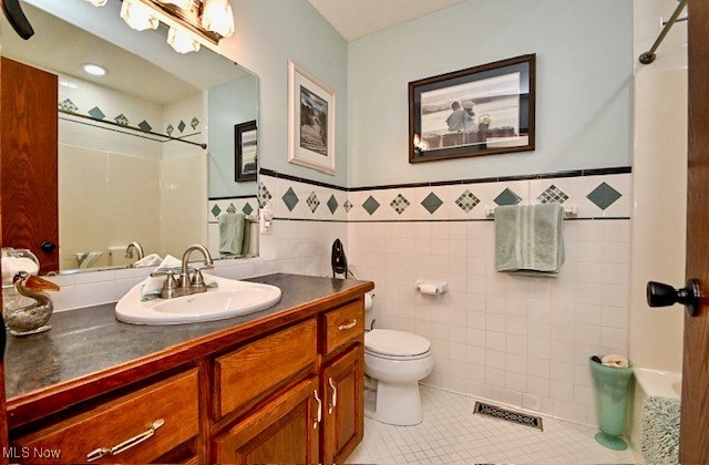 10400 Stoneacre St NW, Canal Fulton, OH 44614 - full bath featuring a shower, tile patterned floors, tile walls, toilet, and a wainscoted wall