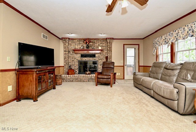 10400 Stoneacre St NW, Canal Fulton, OH 44614 - living area featuring crown molding, ceiling fan, carpet floors, a brick fireplace, and a wainscoted wall