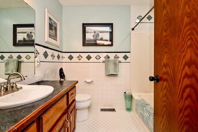 10400 Stoneacre St NW, Canal Fulton, OH 44614 - full bath with tile patterned floors, toilet, vanity, wainscoting, and tile walls