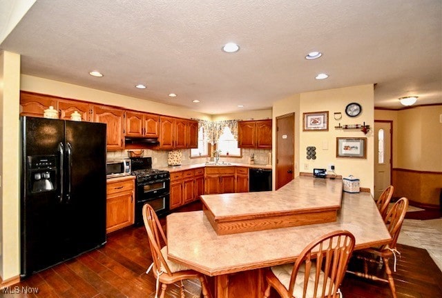 10400 Stoneacre St NW, Canal Fulton, OH 44614 - kitchen featuring black appliances, a peninsula, light countertops, dark wood-style flooring, and brown cabinets