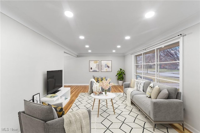 living area featuring light wood finished floors, baseboards, crown molding, and recessed lighting