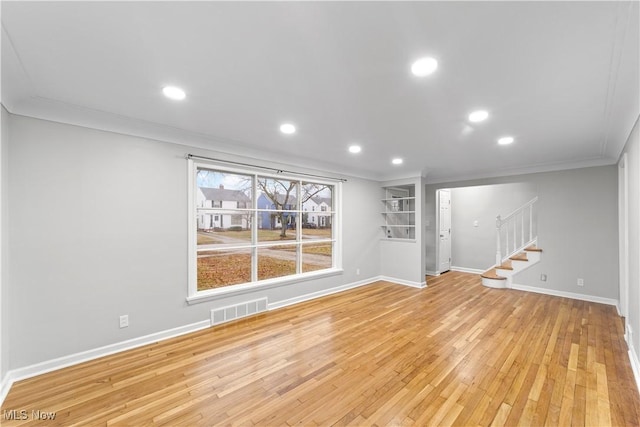 unfurnished living room with stairs, ornamental molding, light wood finished floors, and visible vents