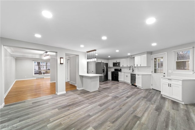 kitchen featuring light wood-style flooring, white cabinets, open floor plan, light countertops, and black appliances