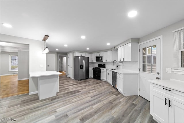 kitchen featuring white cabinets, black appliances, light wood finished floors, and a sink