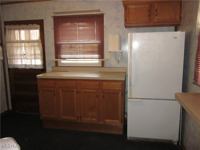 kitchen featuring a healthy amount of sunlight, wallpapered walls, light countertops, and freestanding refrigerator