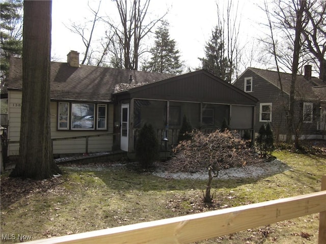 view of front of home featuring a shingled roof, a chimney, and a sunroom