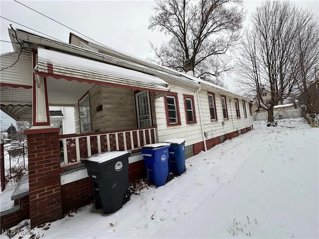 view of snowy exterior featuring covered porch