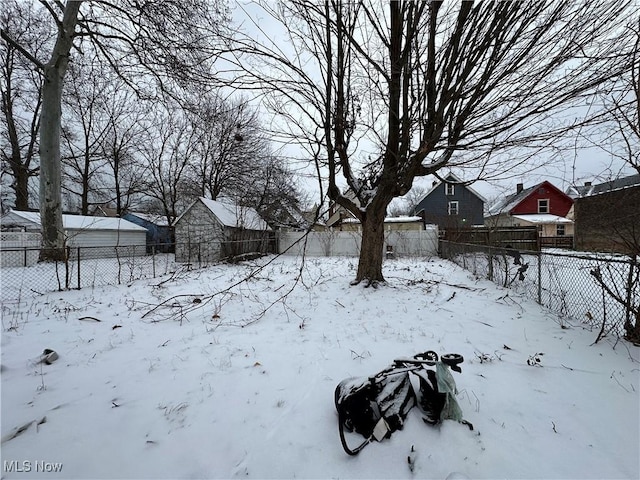 yard layered in snow with an outbuilding and a fenced backyard