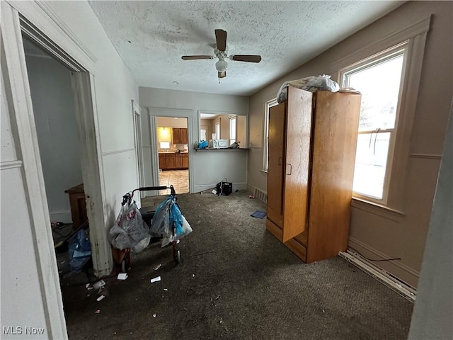 interior space featuring ceiling fan, baseboards, and a textured ceiling