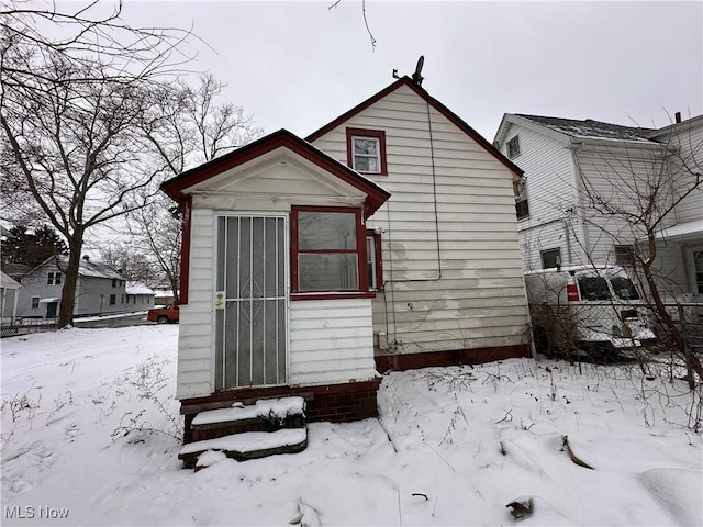 snow covered back of property with a garage and fence