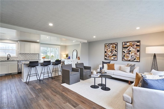 living room featuring a wealth of natural light, dark wood-style flooring, a textured ceiling, and recessed lighting