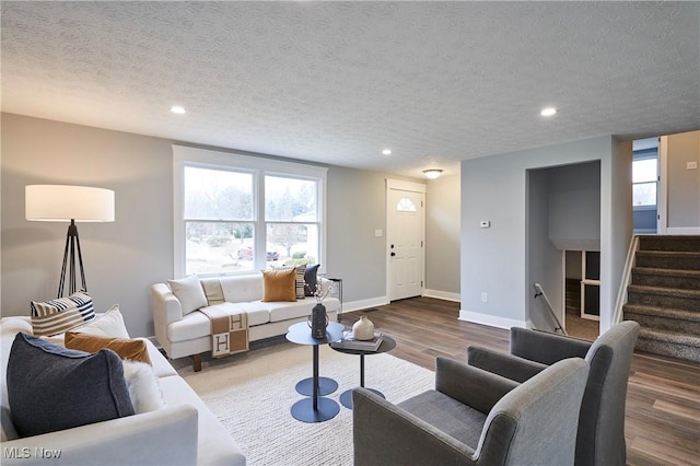 living area with a textured ceiling, stairway, wood finished floors, and baseboards