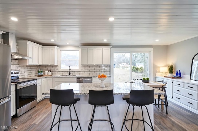 kitchen featuring stainless steel appliances, a kitchen island, a sink, and a kitchen breakfast bar