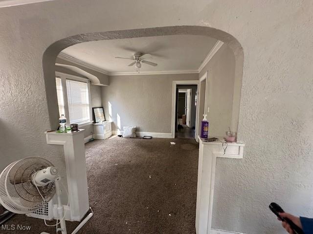 interior space featuring arched walkways, crown molding, and a textured wall