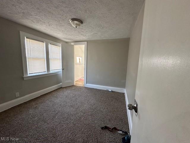 carpeted spare room featuring baseboards and a textured ceiling