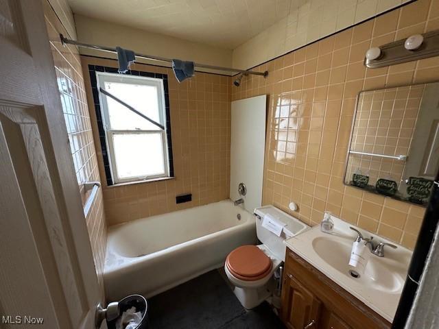 bathroom featuring tile walls, bathtub / shower combination, decorative backsplash, toilet, and vanity