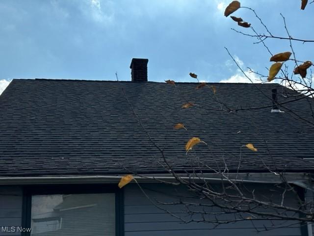 exterior details with a shingled roof and a chimney