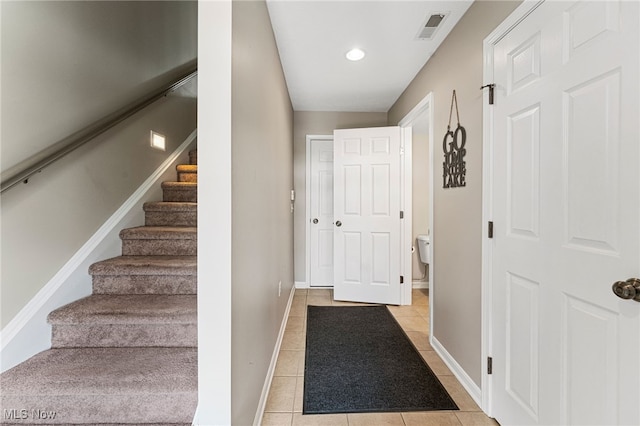 staircase featuring tile patterned flooring, visible vents, and baseboards