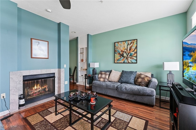 living room featuring a fireplace, baseboards, and wood finished floors