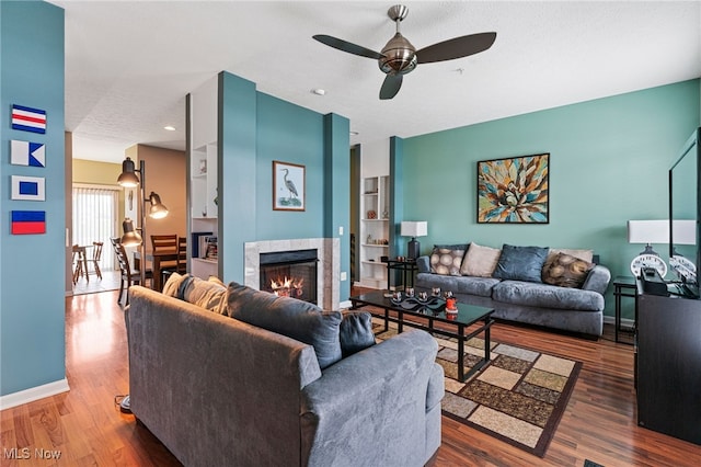 living room with a premium fireplace, ceiling fan, a textured ceiling, wood finished floors, and baseboards