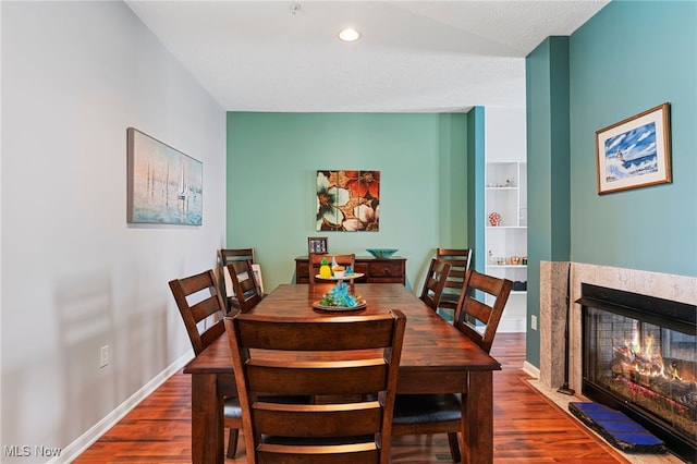 dining area featuring recessed lighting, baseboards, a multi sided fireplace, and wood finished floors