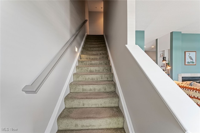 stairs with carpet, a fireplace, and baseboards