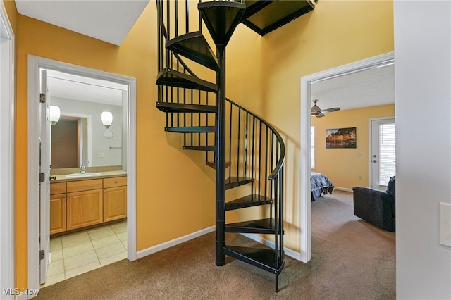 stairway featuring carpet flooring, ceiling fan, baseboards, and tile patterned floors