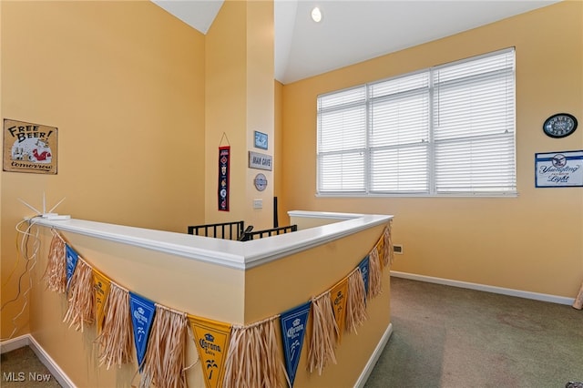 corridor featuring lofted ceiling, carpet floors, and baseboards