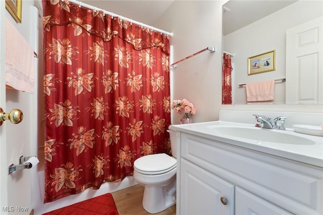 bathroom with toilet, wood finished floors, and vanity