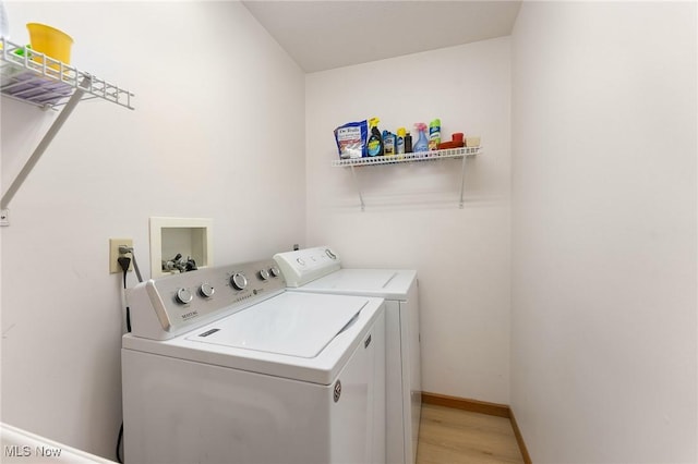 clothes washing area featuring baseboards, laundry area, light wood-style flooring, and washer and dryer