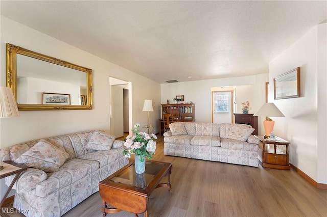 living area featuring visible vents, baseboards, and wood finished floors