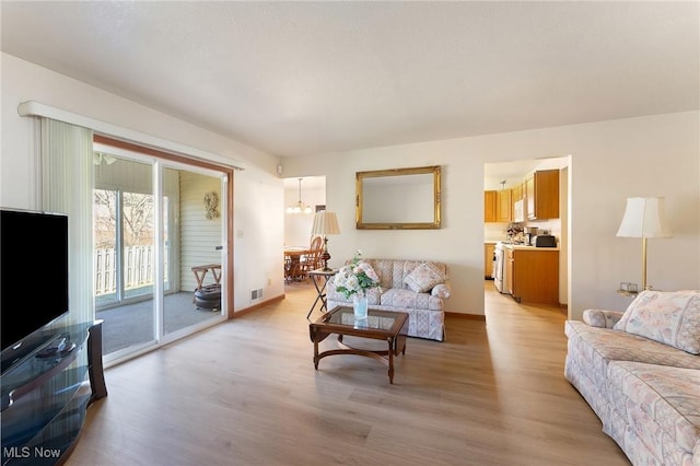 living room with light wood-style floors, baseboards, and a chandelier