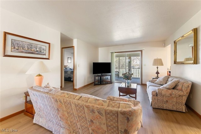 living room featuring a textured ceiling, baseboards, and wood finished floors