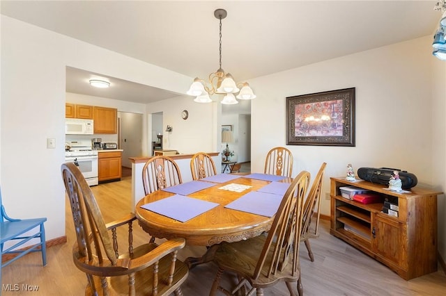 dining room with a notable chandelier, light wood-style flooring, and baseboards