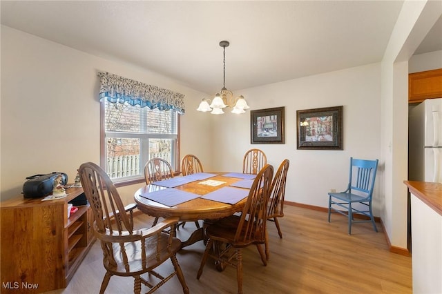 dining room featuring light wood-style floors, a notable chandelier, and baseboards