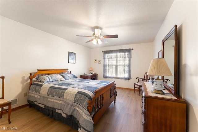 bedroom with visible vents, light wood finished floors, a ceiling fan, and baseboards