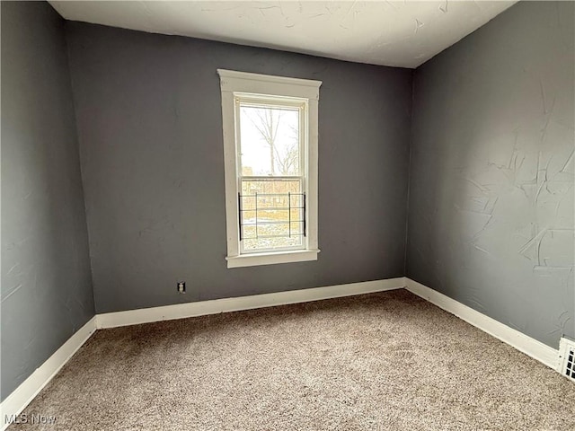 carpeted empty room featuring baseboards