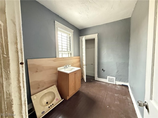 bathroom with visible vents, vanity, baseboards, and wood finished floors