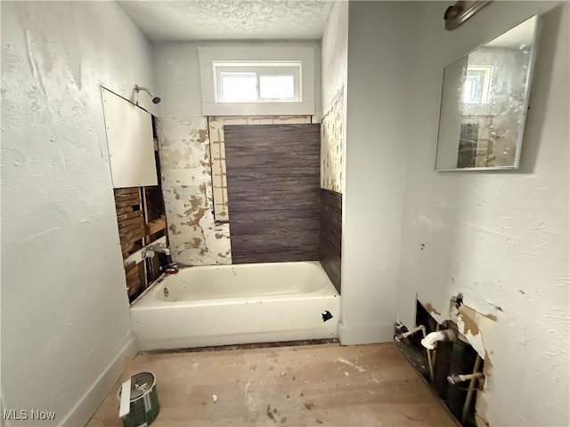 bathroom with a tub and a textured ceiling