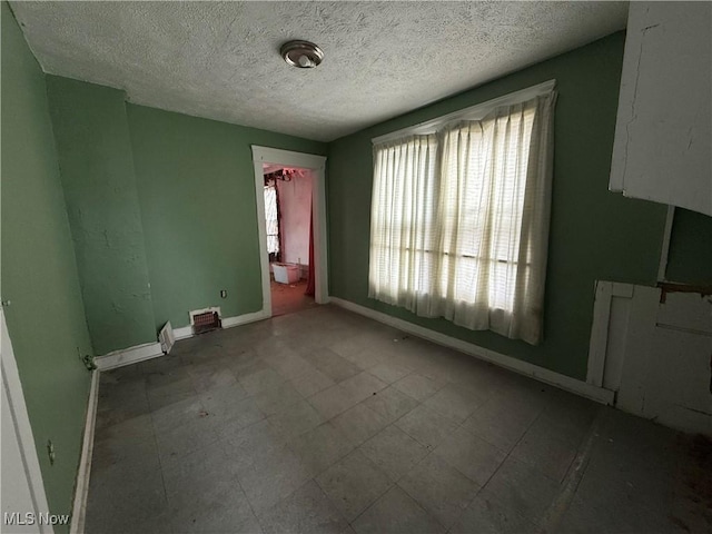 interior space featuring baseboards, a textured ceiling, and tile patterned floors