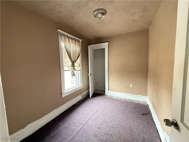 unfurnished room with visible vents, baseboards, and a textured ceiling